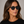 Cord Eco Black square sunglasses with grey lenses worn by female model in her 30s, close-up studio portrait styled with a black T-shirt, highlighting the sleek eco-acetate frame and defined, modern silhouette.