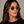 Cord Eco Honey square sunglasses with bottle green lenses worn by female model in her 30s, close-up studio portrait styled with a black T-shirt, highlighting the warm honey-toned eco-acetate frame and defined, contemporary silhouette.