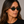 Ellipse Eco Spotted Havana oval sunglasses with mirror green lenses worn by female model in her 30s, close-up studio portrait styled with a black T-shirt, highlighting the patterned eco-acetate frame and clean, balanced silhouette.
