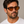 Madras Eco Dark Havana oval sunglasses with orange lenses worn by male model in his 30s, close-up studio portrait styled with white cotton T-shirt.