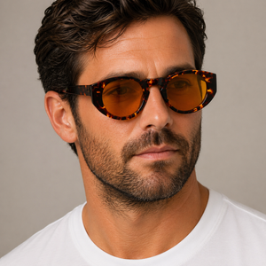 Madras Eco Dark Havana oval sunglasses with orange lenses worn by male model in his 30s, close-up studio portrait styled with white cotton T-shirt.